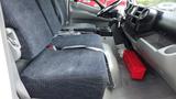 Interior view of a 2016 Hino 195 featuring two fabric seats with seatbelts and a control area with a red toolbox on the floor