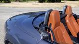 A 2007 Mazda Miata with a sleek design featuring a dark exterior and orange leather seats in the foreground