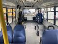 Interior view of a 2016 Chevrolet Express showing rows of blue seats and space for standing passengers with a yellow pole for support on the left side