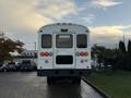 A white 2015 International 3000 school bus viewed from the rear showcasing its taillights and rear door