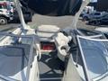 A 2013 Larson 238 boat featuring two captain's chairs and a central lounge seat with a sleek white interior and a laid-back design