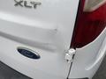 A 2017 Ford Transit Connect with a noticeable dent and scratches on the rear door near the taillight
