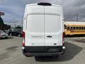A white 2023 Ford Transit van viewed from the rear showcasing its large back doors and simple design