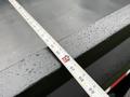 A ruler measuring the edge of a 2022 Ford F-550 with droplets of water on its surface