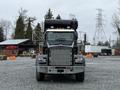 A 2018 Kenworth T800 truck with a black cab and chrome grille is parked in a gravel area, featuring a large black tank mounted on the back and visible headlights and mirrors.