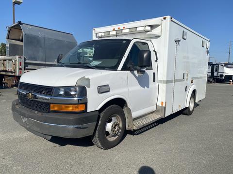 A white 2011 Chevrolet Express cargo van with a boxy shape and rear ambulance-style compartment windows