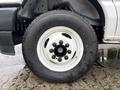 A close-up of a white wheel with a black tire on a 2024 Ford E-450 showing the lug nuts and tread pattern