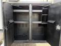 An open storage compartment of a 2012 International DuraStar 4300 with shelves and hooks for organizing tools and equipment