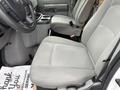 Interior view of a 2024 Ford E-450 showing two front seats with light gray fabric upholstery and a console in between