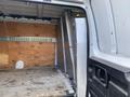A 2023 GMC Savana van interior showing a spacious cargo area with wooden paneling and a metal partition in the rear