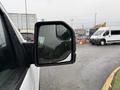 A side mirror of a 2018 Ford F-150 reflecting a wet surface with water droplets on the glass