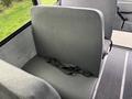 A gray upholstered bench seat designed for passengers featuring a safety belt attached to the side
