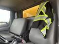 Interior of a 2019 Hino 155 truck featuring two gray seats with a high-visibility safety vest draped over one seat and a black jacket on the other seat