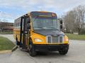 A 2022 Freightliner B2 school bus with a bright yellow exterior and an open door is positioned at an angle showcasing its front and side features