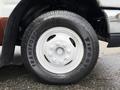 A close-up of a white tire on a 2014 Ford Econoline with the brand name Firestone visible on the sidewall and a five-spoke wheel design