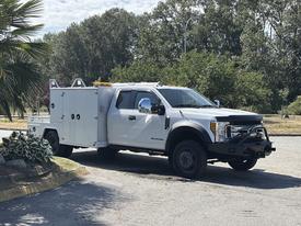 A 2017 Ford F-550 truck with a white body and utility bed featuring storage compartments and a black front bumper