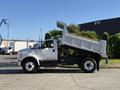 A 2017 Ford F-650 Super Duty dump truck with an elevated bed, shown from the side, featuring a white exterior and black chassis