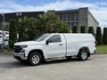A 2019 Chevrolet Silverado 1500 in white with a covered bed and silver side steps parked on a concrete surface