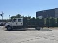 A white 2011 International 4300 flatbed truck with a black stake side attached parked on a lot