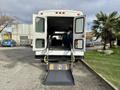 A 2002 Ford Econoline with its rear doors open displaying a wheelchair ramp in the lowered position