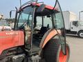 A 2010 Kubota M6040 tractor with a red and black exterior featuring a glass cabin and large rear tires