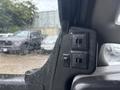Close-up of the window controls on the driver's side of a 2018 Chevrolet Express featuring two switches and a toggle switch in a wet environment