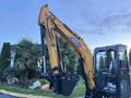 A 2023 Sany SY35U mini excavator with a yellow arm and black bucket in the foreground