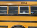 A yellow 2006 Thomas Saf-T-Liner HDX school bus showing emergency exit signage and several windows