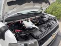 A 2020 Chevrolet Express with the hood raised revealing the engine compartment showcasing various components including hoses and a white coolant reservoir
