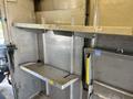 A 2012 Ford Econoline interior with metal shelving units and open space for storage