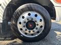 Close-up of a shiny steel wheel with multiple lug nut holes and a black tire mounted on a 2020 Peterbilt 330