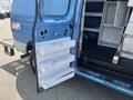 A blue 2005 Ford Econoline van with a side door open revealing metal shelves labeled with various names