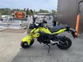 A bright yellow 2018 Honda Grom motorcycle with a black seat and black wheels parked on a concrete surface