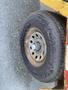 A tire mounted on a metal wheel with visible tread and rust spots on the rim
