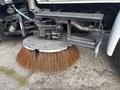 A close-up of a circular street sweeper brush mounted on a 2012 International DuraStar 4300 with long bristles ready for cleaning surfaces