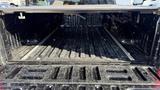 A 2016 Ford F-150 truck bed shown from the rear with a rugged and textured surface featuring metal tracks along the sides