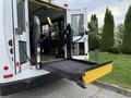 A 2015 Chevrolet Express with a wheelchair lift extended from the rear doors showcasing the platform and hand controls