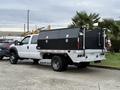 A 2016 Ford F-550 Super Duty with a white cab and black toolboxes in the truck bed facing right