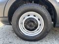 Close-up of a black wheel rim with a silver circular hubcap mounted on a treaded tire of a 2019 Ford Transit 350