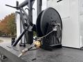 A black reel and mounted equipment with a hose attached on a flatbed truck designed for heavy-duty work