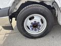A close-up view of a wheel on a 2018 Chevrolet Express featuring a silver rim and a black tire with blue lug nuts