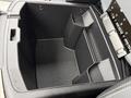 Open center console storage compartment of a 2018 RAM 1500 featuring multiple sections and a textured bottom
