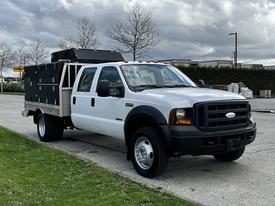 A 2007 Ford F-550 truck with a white cab and a silver flatbed featuring a black tool box on the back