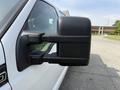 A close-up of the side mirror of a white 2011 Ford F-350 SD highlighting its black casing and adjustable features