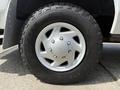 Close-up of a silver alloy wheel with a five-spoke design mounted on a rugged black tire branded Cooper Discoverer AT3