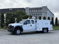 A white 2008 Ford F-450 truck with a utility body and tools on the side parked on a concrete surface