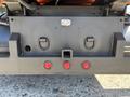 The rear underside of a 2016 Isuzu NPR-HD showing metal connections and red indicator lights
