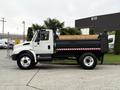 A 2006 International 4200 dump truck in white with a black dump bed and red reflective striping on the side
