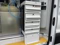 A 2023 Ford Transit with a white storage unit featuring multiple drawers labeled for tools and equipment
