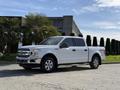 A white 2018 Ford F-150 pickup truck parked on a paved surface with a shiny exterior and four doors